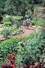 Stone path winding through blooming lilacs and greenery beside Miramont Castle.