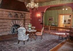 Victorian-style sitting room with antique furniture and ornate fireplace.
