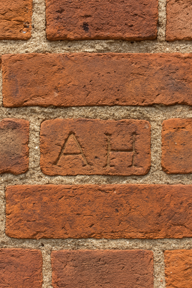 Close-up of red brick wall with the initials 