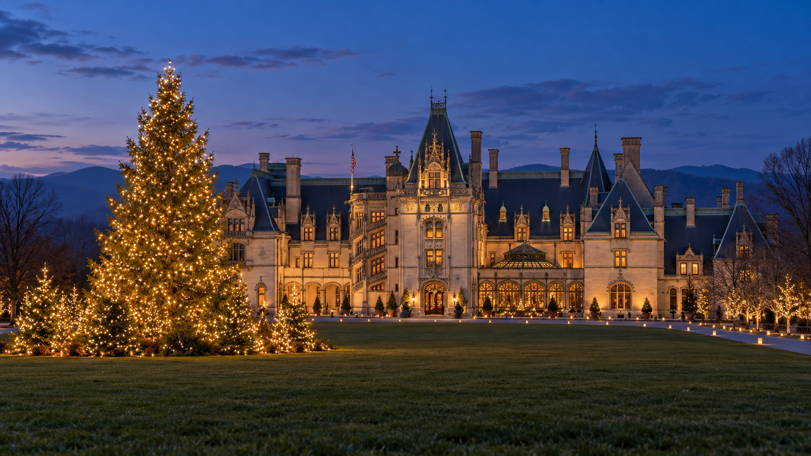 Wide evening view of Biltmore House with a glowing Christmas tree and illuminated Front Lawn.